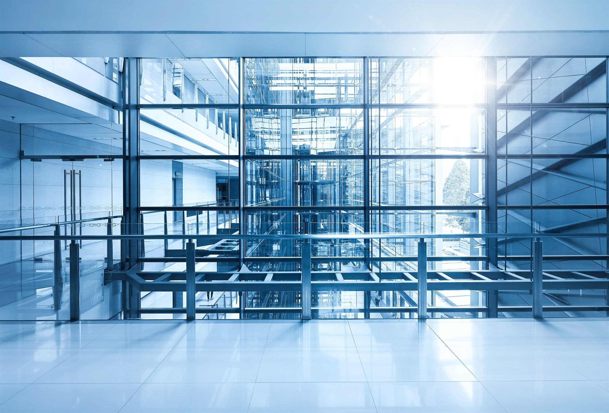 Commercial Mold Inspections — The daylit interior of an empty modern commercial building with glass curtain walls and exposed structural columns (illustrative)